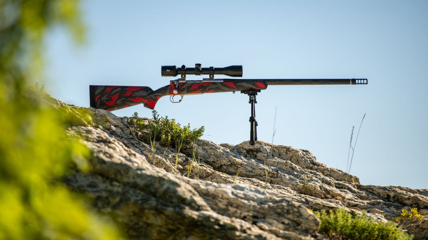 Riflescope on a stand with a clear blue sky and rocky landscape